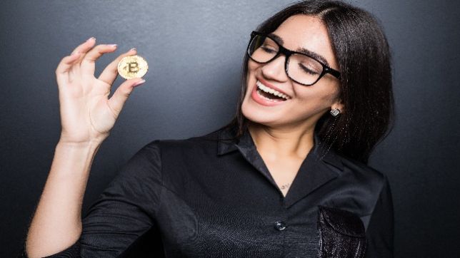 20260125005147young successful confident woman with glasses holds gold bitcoin her hand isolated black wall